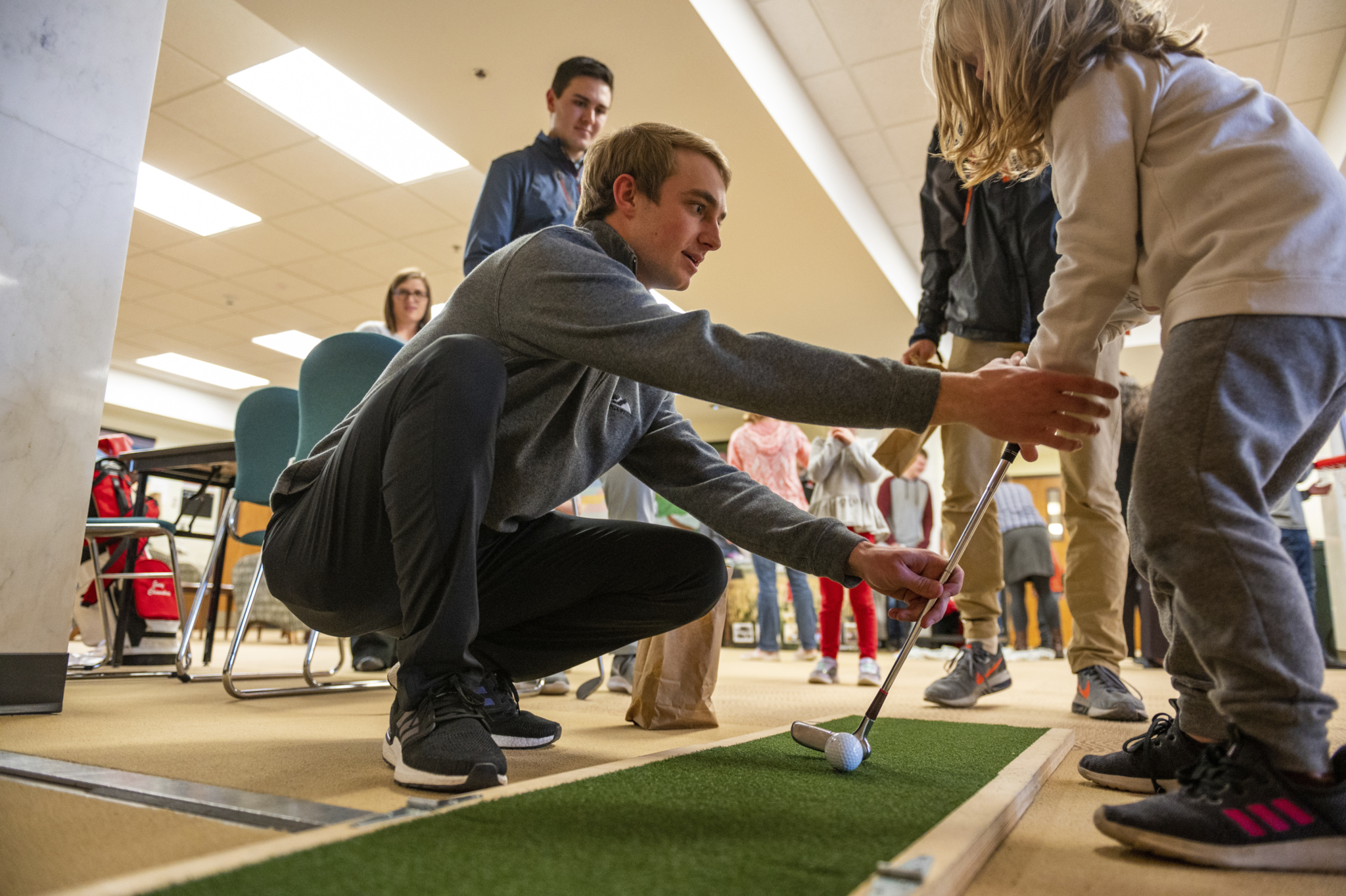 A professional golf management student demonstrates proper putting techniques to a child during CASNR Community night