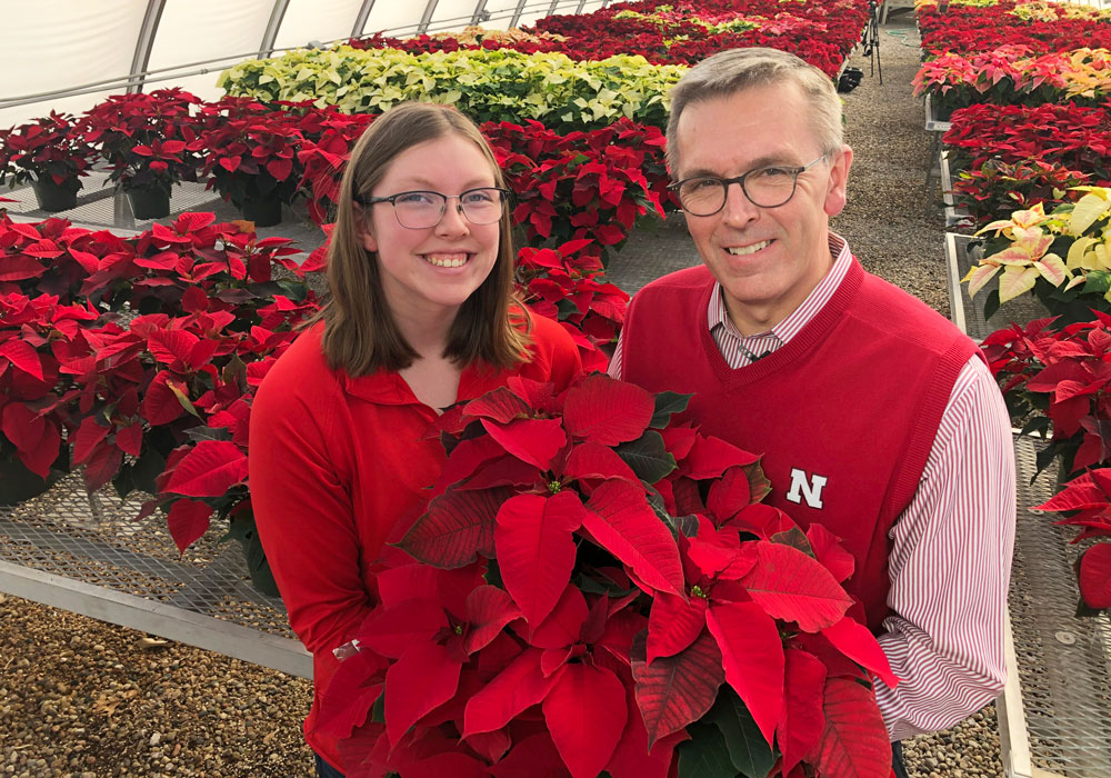 Horticulture Club president Christine Barta and Chancellor Ronnie Green hold poinsettia plant in front of them