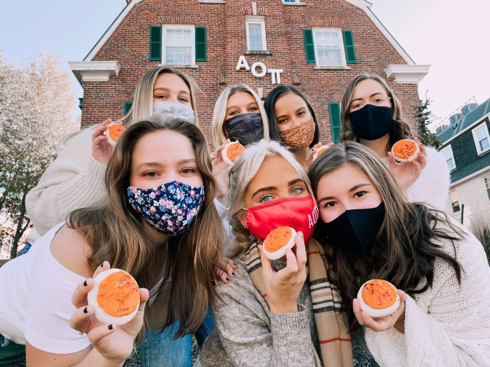 Girls in front of a sorority house wearing face masks