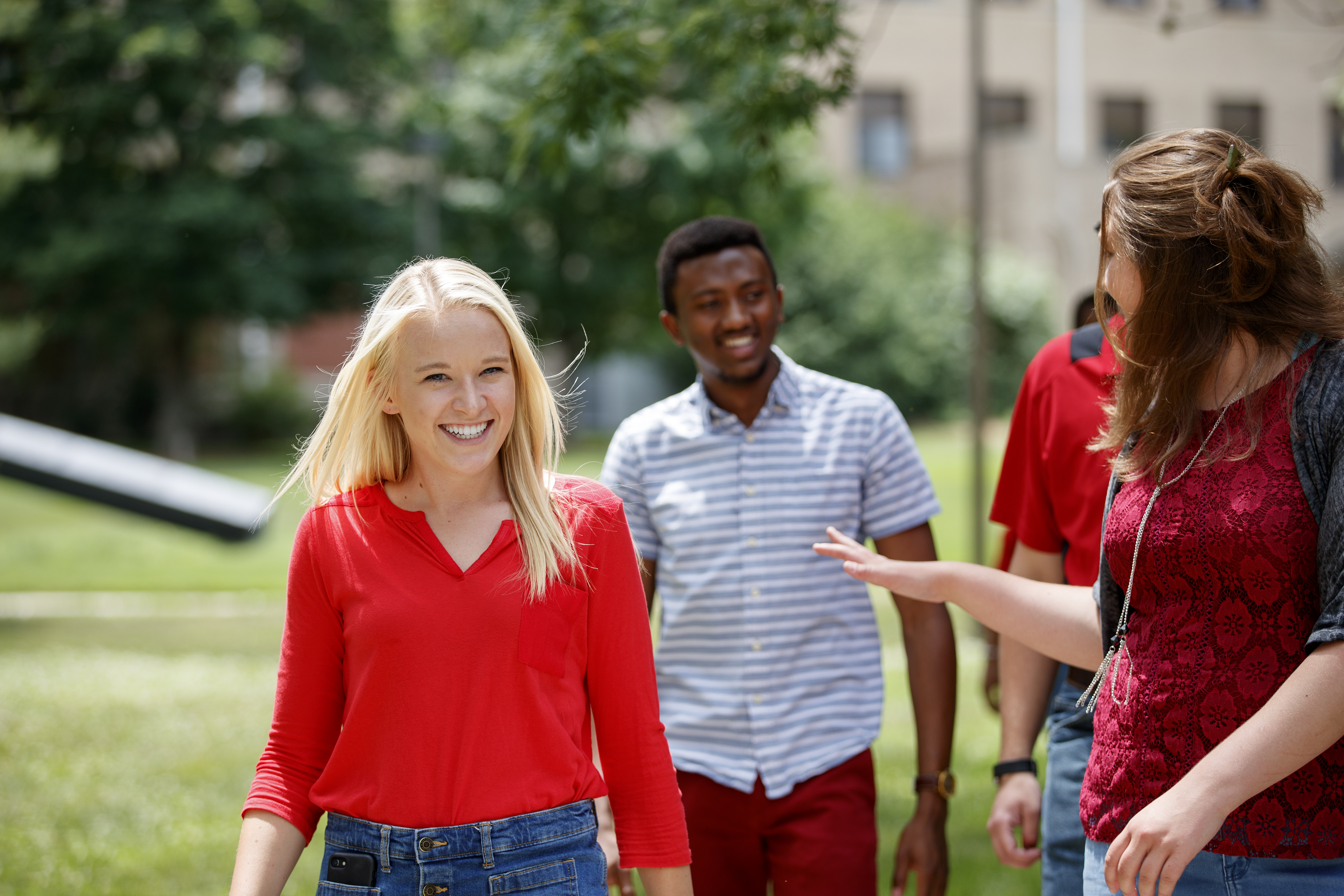 Three students converse and laugh while walking around East Campus
