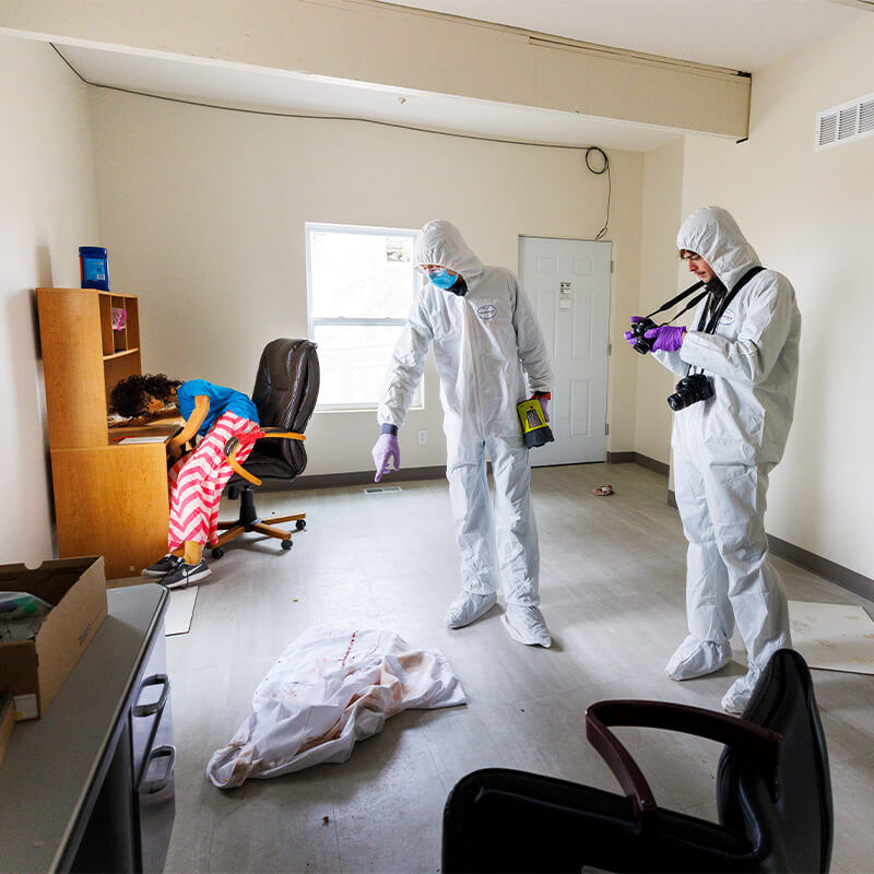 Student researchers examine and photograph a crime scene