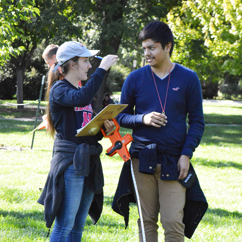 Students talking while standing by tree