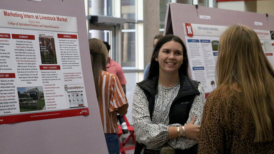 A student conducts a poster presentation about her animal science internship.