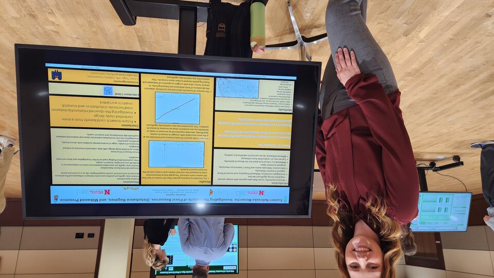 A student poses by her research poster at the Spring 2025 Environmental Studies Showcase.
