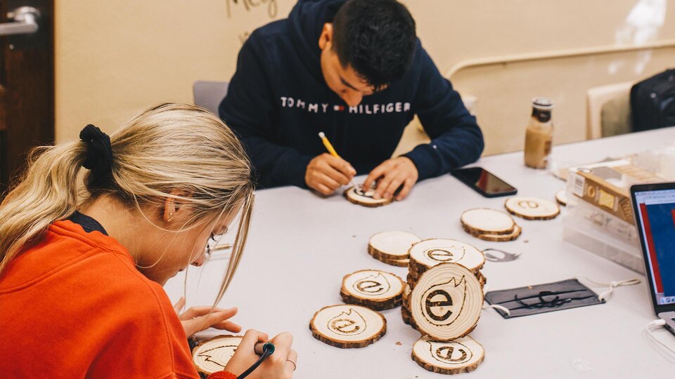 Two students burning the Engler Agribusiness Entreprenuership logo onto wooden coasters