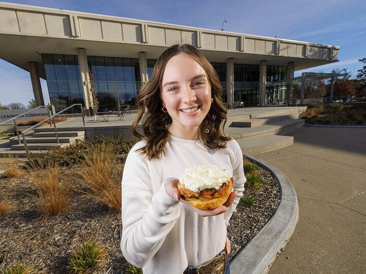 Alexa Carter poses holding her chili roll creation in front of the Dinsdale Family Learning Commons on East Campus.