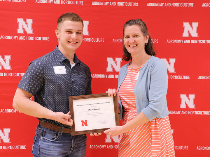 Mason Rutgers posing with a certificate for an undergraduate teaching assistant award