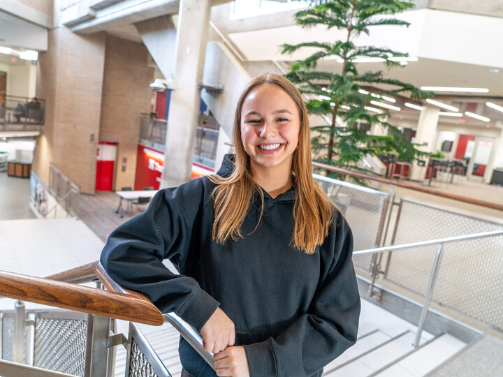 Ella, a Cultivate ACCESS Ambassador, poses by the staircase in the Nebraska East Union