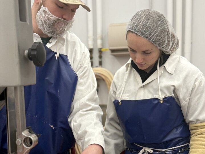 Steven Rogers points to a large piece of meat as he instructs a student worker.