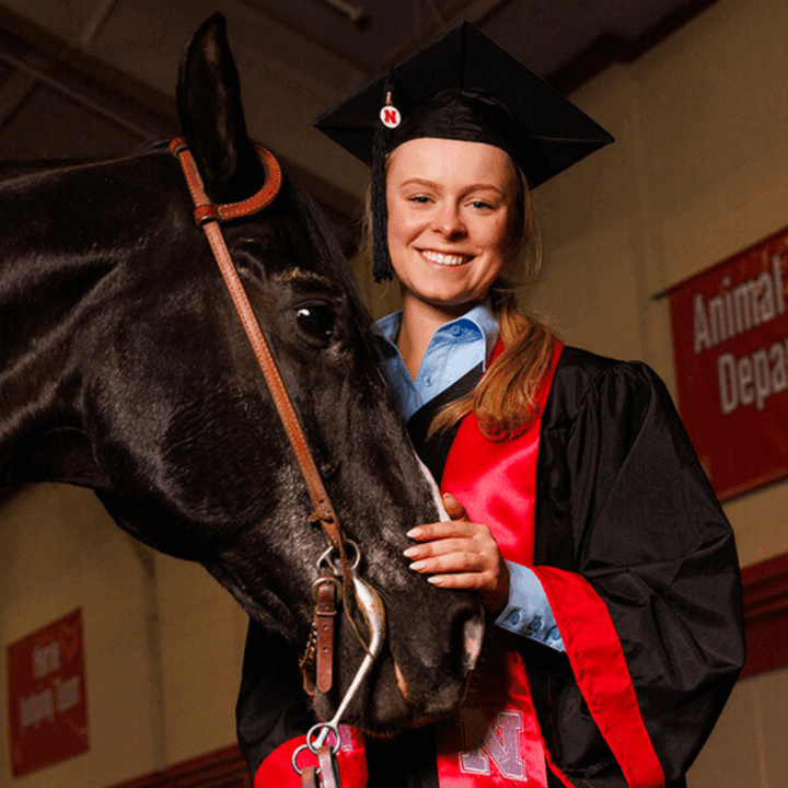 Izzi Velinsky in cap and gown with a horse