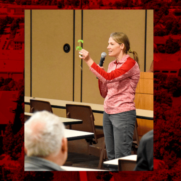 Jennifer Brhel holding a small plant and teaching in a classroom