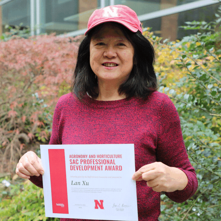 Lan Xu in Keim Hall courtyard holding award